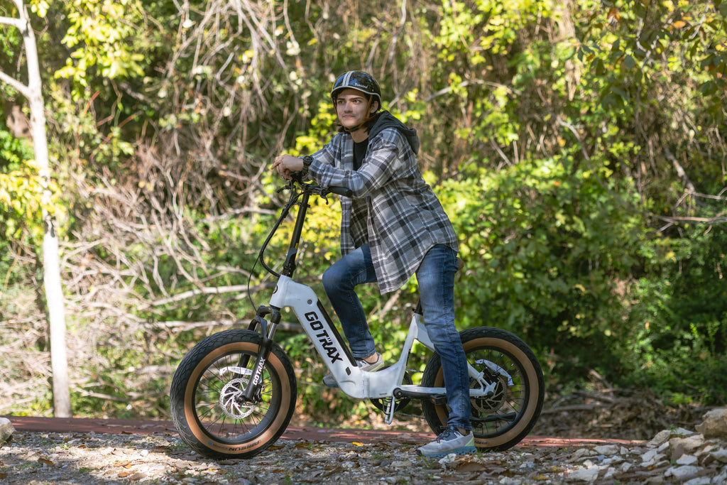 A man leaning on the GOTRAX F5 electric bike with a foldable frame and fat tires.