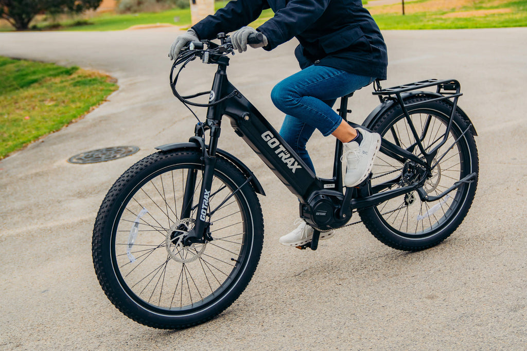 A shot of a woman riding the GOTRAX MX1 Mid Drive Electric Bike with a rear rack and superior hill performance.